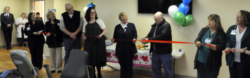 The Inter-Mountain photo by Beth Henry-Vance Cardiac rehabilitation patient Bill Valentine, of Glenmore, cuts the ribbon Monday at the new cardiac and pulmonary rehabilitation facility at Davis Medical Center, while hospital officials and community members join in the celebration